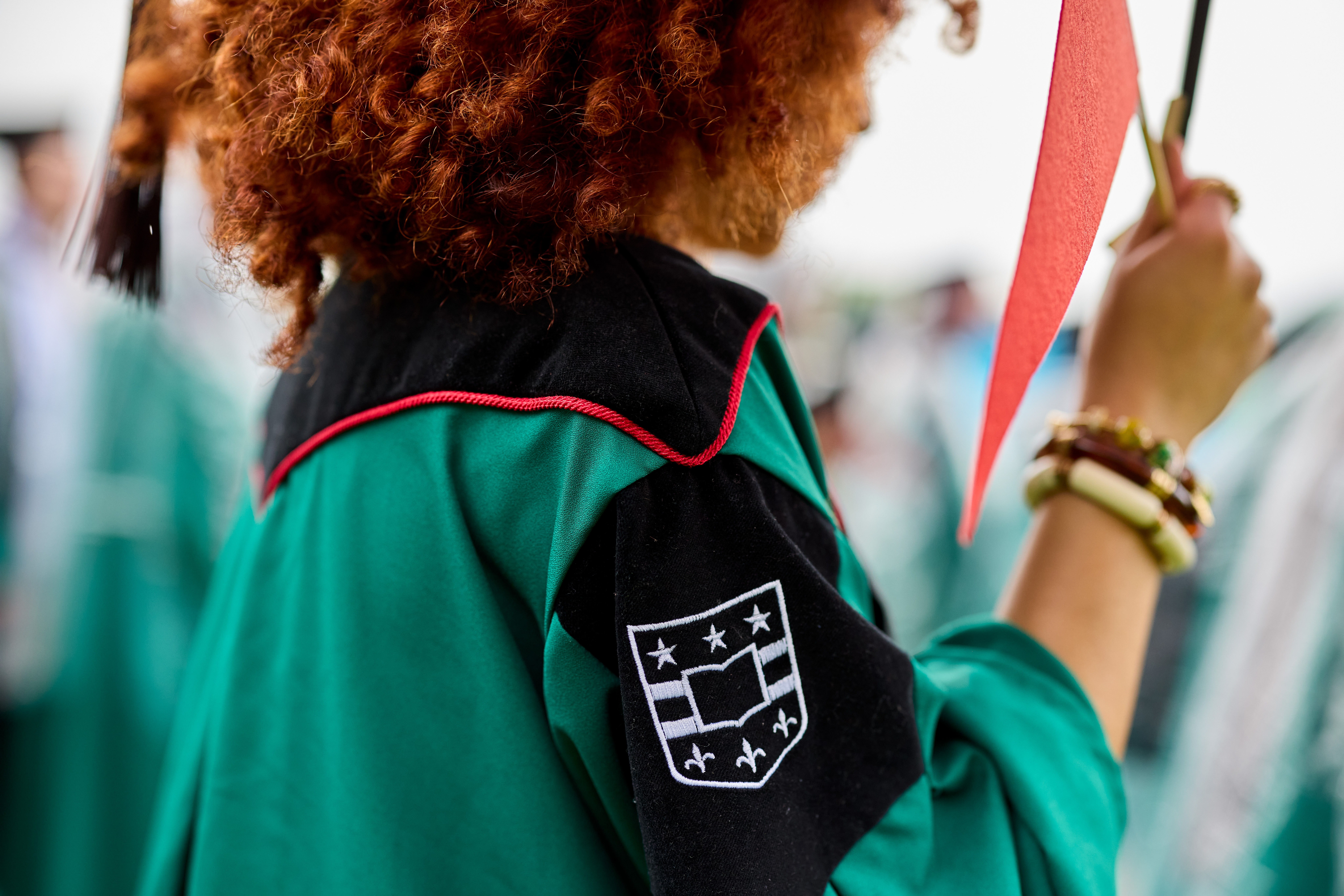 Graduate wearing the WashU regalia, displaying the University shield embroidered on the shoulder.